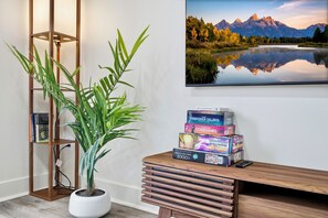 Una habitación con un escritorio de madera, una planta en maceta y un cuadro con un paisaje.