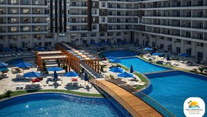 Ein modernes Hotel mit mehreren Schwimmbecken, Liegestühlen und Sonnenschirmen.