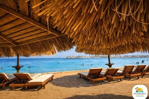 Ein Strandloungebereich mit Holzliegen und einer Struktur mit Reetdach.