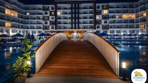Ein Hotel mit Pool, einer Holzbrücke und mehreren Balkonen.