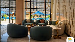 Eine moderne Hotelhalle mit großen Fenstern, bequemen Sitzgelegenheiten und Blick auf den Poolbereich.