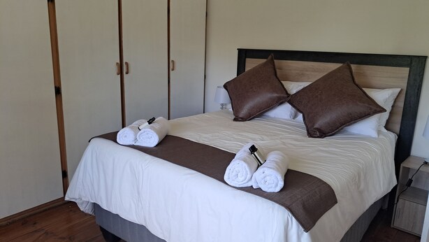 A neatly made bed with white linens, two brown pillows, and two rolled towels on the bed. - Peaceful, quiet, and safe family friendly home (Rosendal)