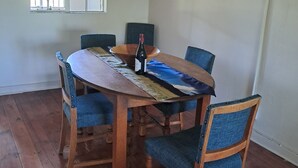 A dining area with a wooden table, blue upholstered chairs, and a bottle of wine. - Peaceful, quiet, and safe family friendly home (Rosendal)