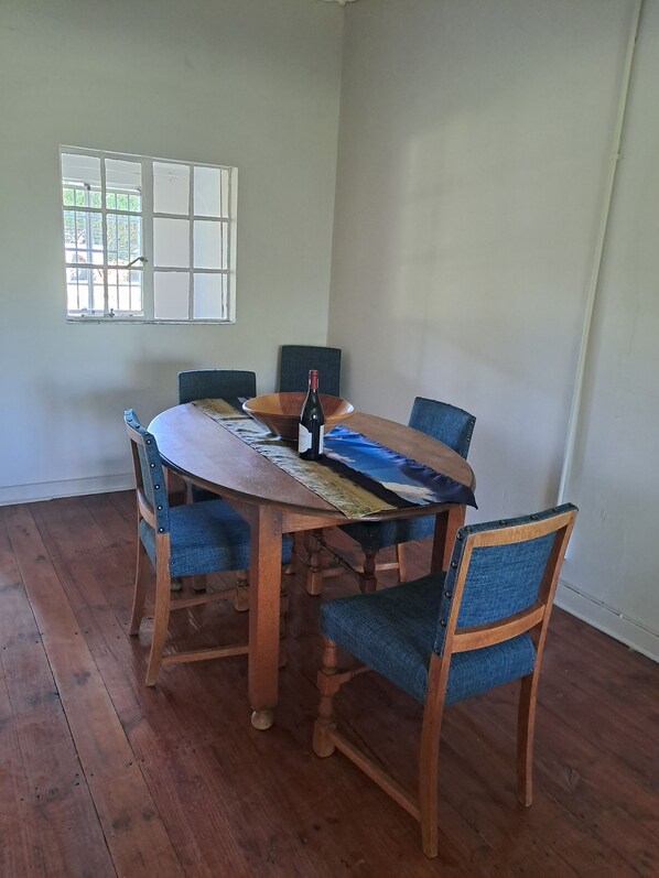 A dining area with a wooden table, blue upholstered chairs, and a bottle of wine.