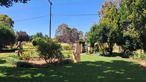 A well-maintained garden with a stone bench, a variety of shrubs, and a tall tree. - Peaceful, quiet, and safe family friendly home (Rosendal)