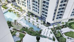 Et højt hotel med flere balkoner, en swimmingpool og udendørs siddeområder.