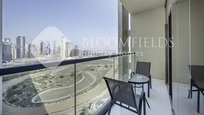 En balkon med udsigt over byens skyline og en flod.