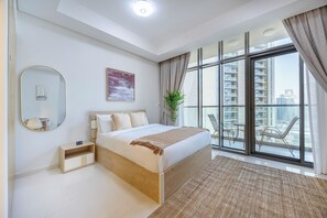 Ein modernes Schlafzimmer mit einem großen Bett, einem Nachttisch, einem Spiegel und Blick auf die Stadt durch große Fenster.