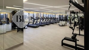 Et moderne fitnesscenter med løbebånd, styrkemaskiner og et stort spejl, der reflekterer rummet.