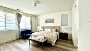 A modern bedroom with a large bed, a bench, a chair, and a bedside table. - Quiet place (Spanish Springs)