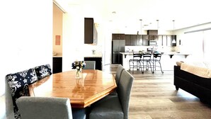 A modern kitchen with dark cabinets, a central island, and a dining area with a wooden table and grey chairs. - Quiet place (Spanish Springs)