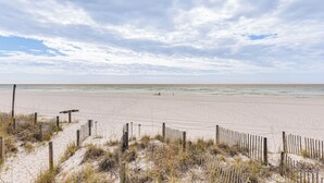 Ein Strand mit einer Holzlattenzaun und einem Wegweiser.