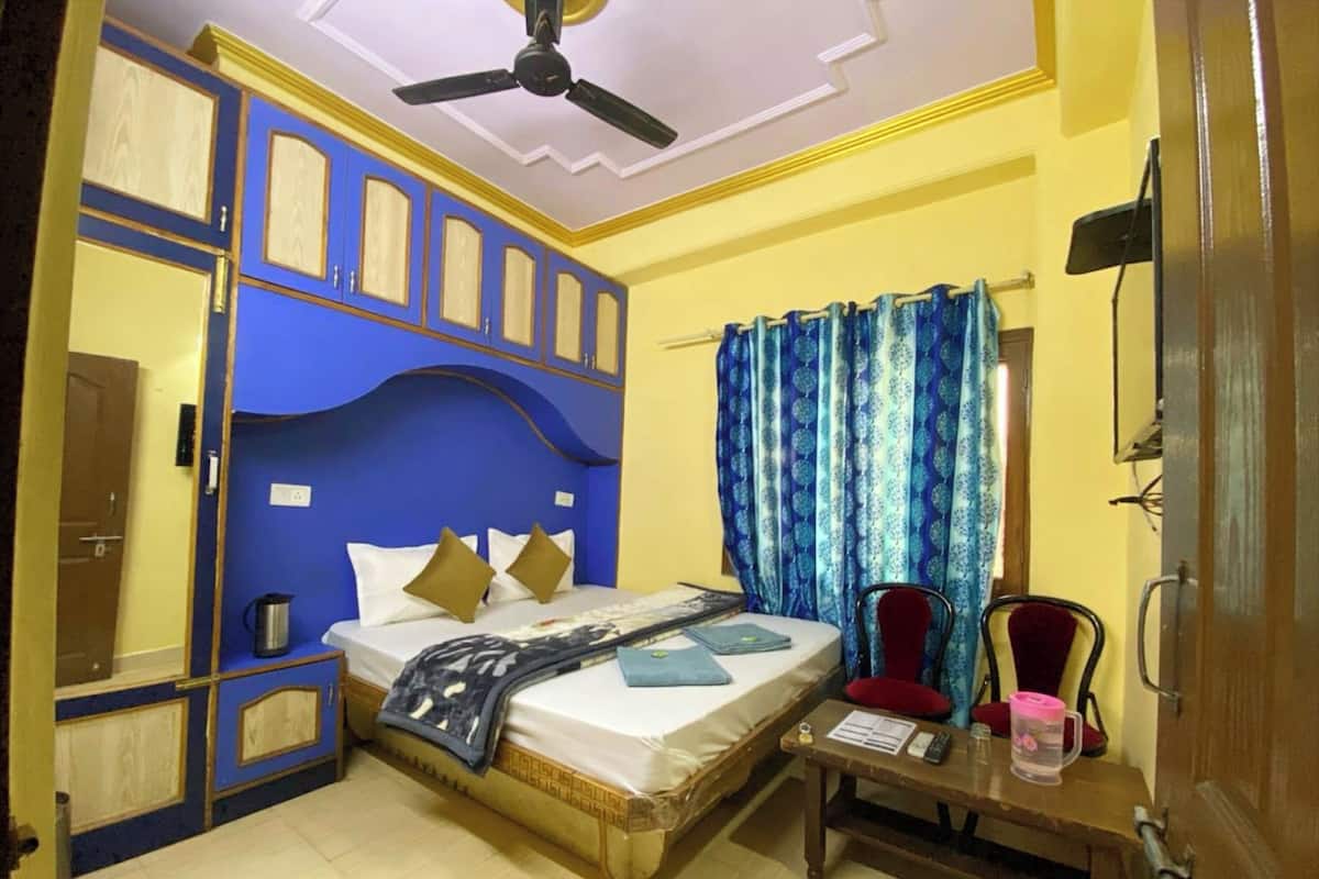 Un dormitorio con cama, mesita de noche, silla y ventilador de techo.