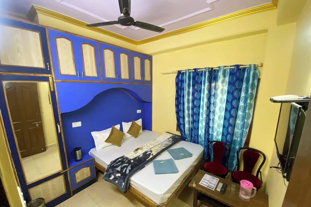 Una habitación con cama, escritorio, silla, ventilador de techo y ventana con cortinas.