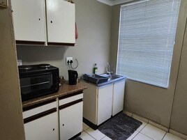 Una cocina compacta con microondas, pileta y alacenas.