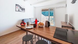 Eine moderne Küche mit Holzarbeitsplatte, Barhocker und einem Esstisch. Ein Fenster bietet Blick ins Grüne.