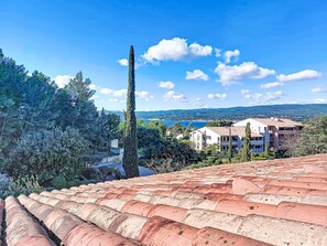 A coastal town with terracotta rooftops, a prominent tall tree, and buildings with balconies overlooking the sea. - Hauts de la Madrague by Interhome (Saint Cyr sur Mer La Madrague)