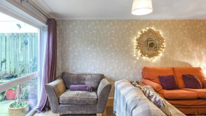 Una sala de estar con sofá, sillón y una lámpara de pared decorativa.