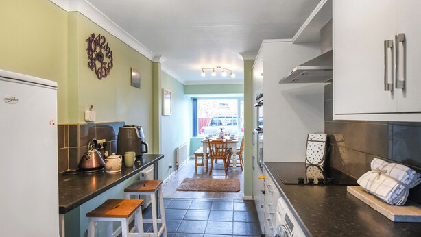 Una cocina equipada con refrigerador, estufa, lavaplatos y un comedor con sillas y mesa.