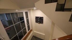 Una escalera con barandal de madera, puerta de cristal y un cuadro en la pared.
