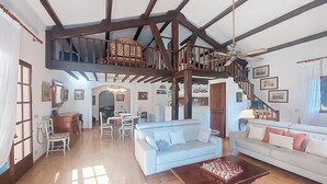 A spacious living area with a high ceiling, wooden beams, a staircase, and a dining area. - La Maisonnette by Interhome (Le Val)