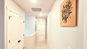 Un couloir doté de revêtements de sol en moquette, de murs blancs et d’un plafond pourvu d’un éclairage encastré.