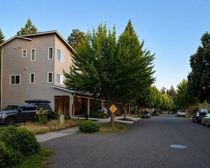 Eine Wohnstraße mit Häusern, geparkten Autos und blauem Himmel.
