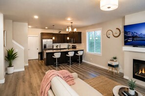 A modern kitchen with dark wood cabinets, a stainless steel refrigerator, and a central island with bar stools. - Cozy and Peaceful Queen's Bedroom 1 (Salem)