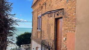Un étroit sentier de pierres mène à un bâtiment en briques doté d’une porte en bois et d’une petite fenêtre.
