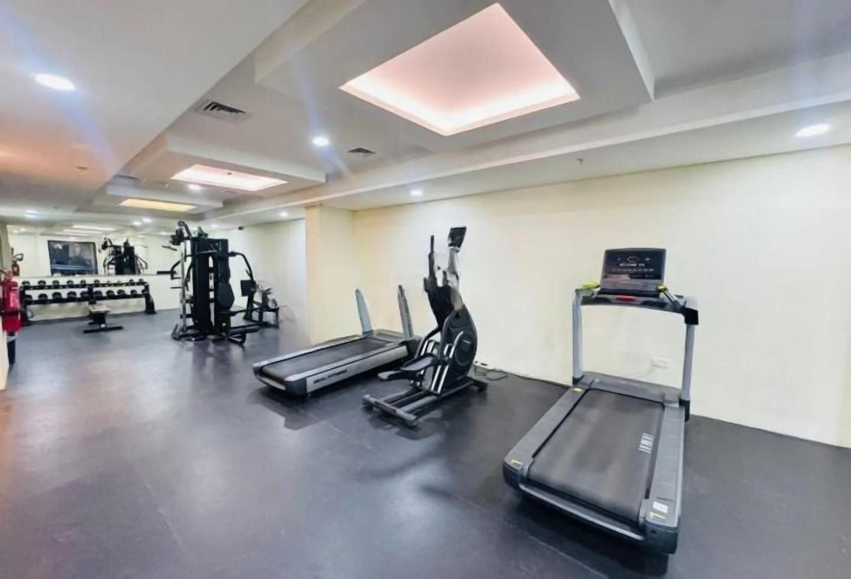 A gym with treadmills, elliptical machines, and weightlifting equipment.