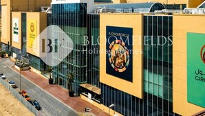 A modern building with the sign "Circle Mall" and a large advertisement for "Bloomfields Holiday Homes". - Bloomfields Modern Escape Stu In Jvc (Dubai)