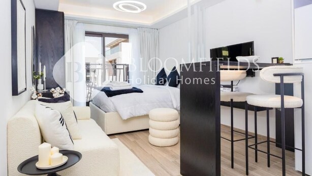 A modern hotel room with a bed, a sofa, a dining area, and a view of the balcony. - Bloomfields Modern Escape Stu In Jvc (Dubai)