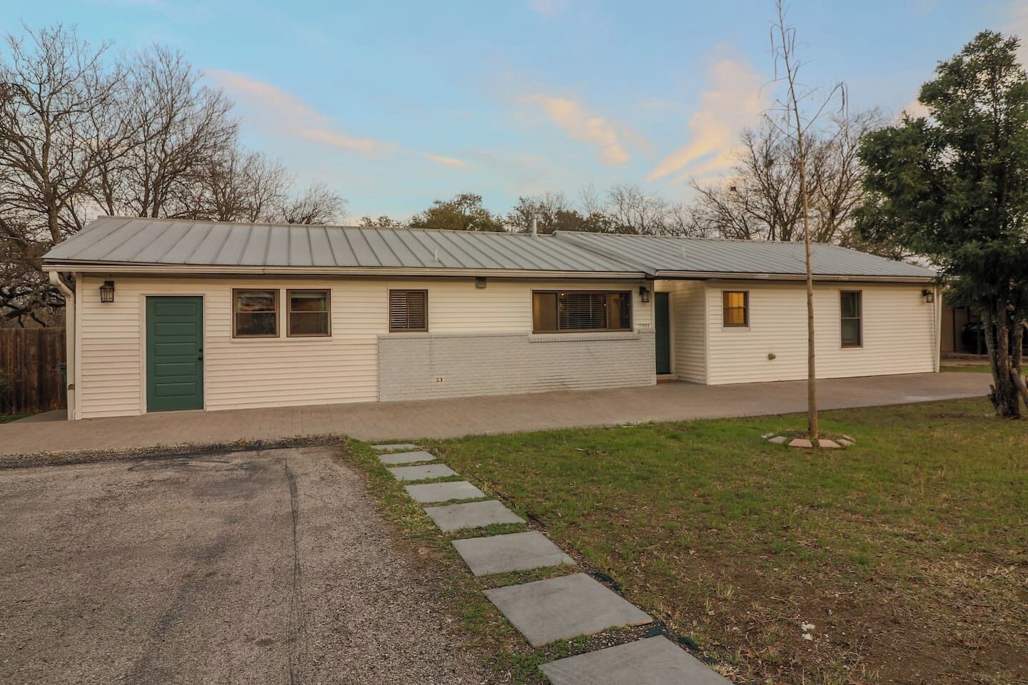 A single-story house with a green door, windows, and a metal roof.