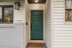 A green door with a doormat that reads "so happy you're here." - South Austin Home | 4BR/2BA, Sleeps 10 | 15 min to DT (Austin)