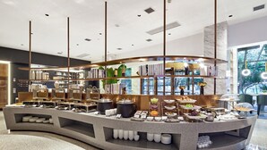 A modern buffet setup with a curved counter, various food items, and a view of greenery outside. - Xi'an waya hotel (Xi'an)
