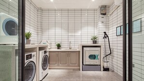 A modern laundry room with a washing machine, dryer, and a vacuum cleaner. - Xi'an waya hotel (Xi'an)