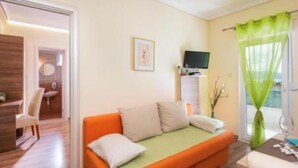A room with a sofa, a television, and a window with curtains.