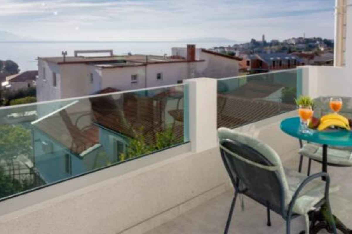 A balcony with a table set for two, overlooking a cityscape.