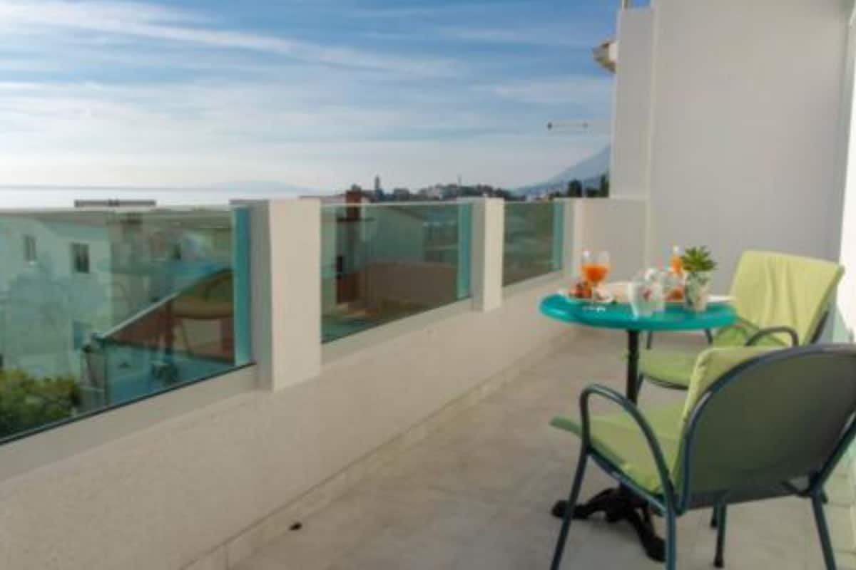 A balcony with a glass railing, a table with chairs, and a view of the cityscape.