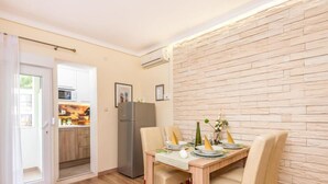 A compact living space with a dining area, kitchenette, and a view through an open door.