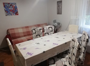 A small, cozy room with a sofa, a dining table, and a fan. - Family-friendly Crikvenica Retreat (Crikvenica)