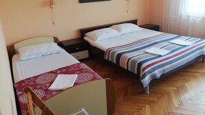A hotel room with two beds, a nightstand, a painting on the wall, and a window with curtains. - Family-friendly Crikvenica Retreat (Crikvenica)