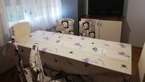A dining area with a table covered in a floral tablecloth, two chairs, a refrigerator, and a television on a cabinet. - Family-friendly Crikvenica Retreat (Crikvenica)