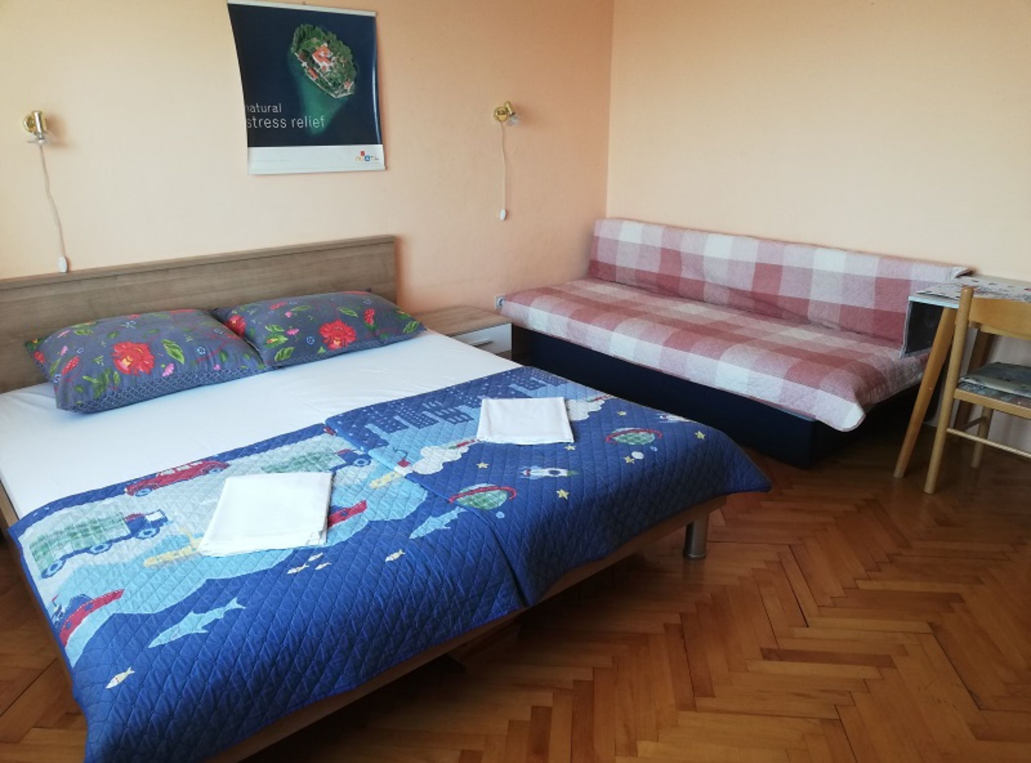 A bedroom with a bed, a bench, and a poster on the wall.