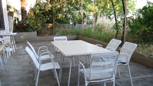 An outdoor patio with a rectangular table and six white chairs. - Family-friendly Crikvenica Retreat (Crikvenica)