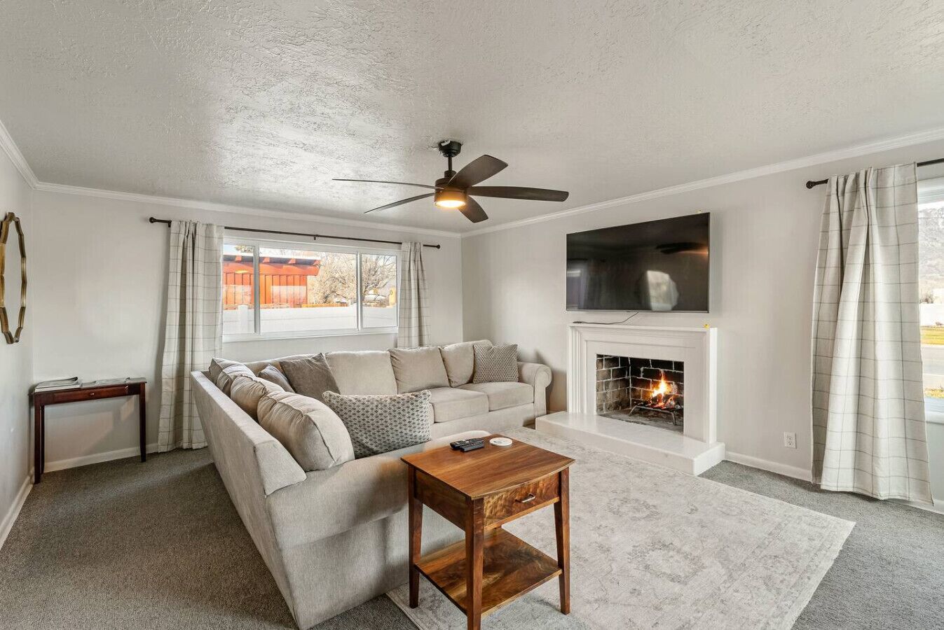 A living room with a sofa, a coffee table, a fireplace, and a ceiling fan.