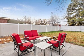 Un patio con una mesa y cuatro sillas rojas.