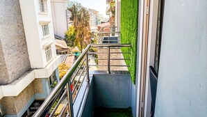 A narrow balcony with a metal railing, a green artificial grass wall, and a view of neighboring buildings. - Hotel Ambrosia (Gangtok)