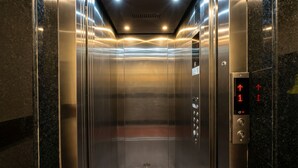 An elevator with metallic walls and a control panel with directional arrows. - Hotel Ambrosia (Gangtok)