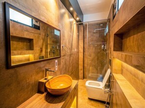 A modern bathroom with a wooden vanity, a large mirror, a glass shower enclosure, and a white toilet.